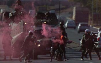 Militantes jogam bomba de fumaça durante desfile de tanques